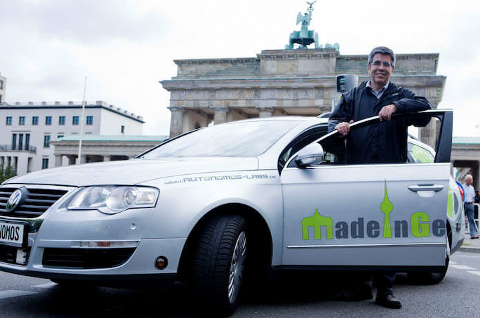 Prof. Dr. Raúl Rojas von der FU Berlin Dahlem mit einem Prototypen eines autonomen VW vor dem Brandenburger Tor in Mitte (Foto: Autonomos-labs.com)